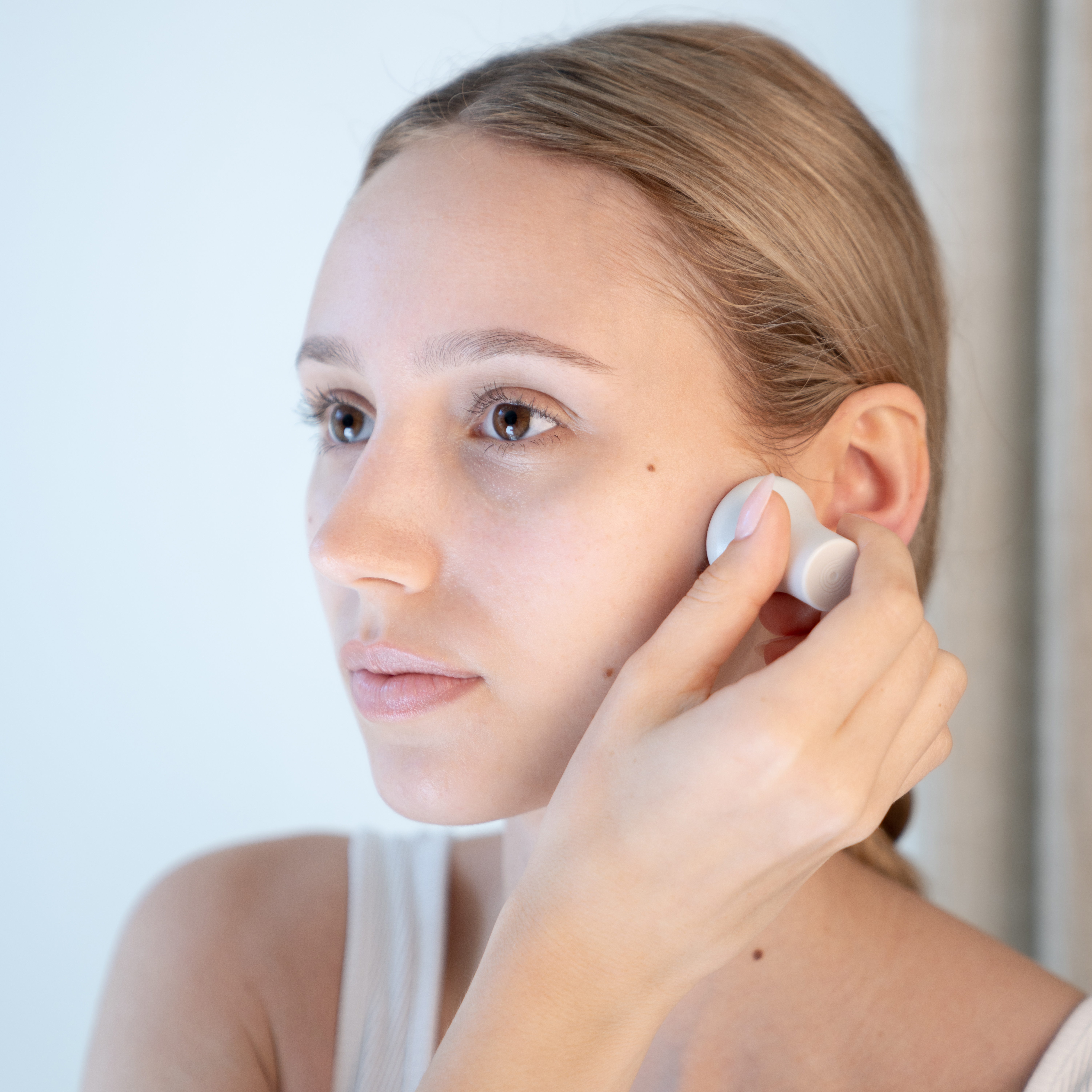 Atmospheric image of a woman using a facial device on her cheek